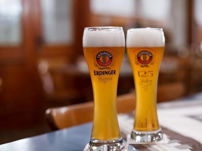 Zwei Gläser Erdinger Weißbier auf einem Tisch in einem gemütlichen Wirtshaus.