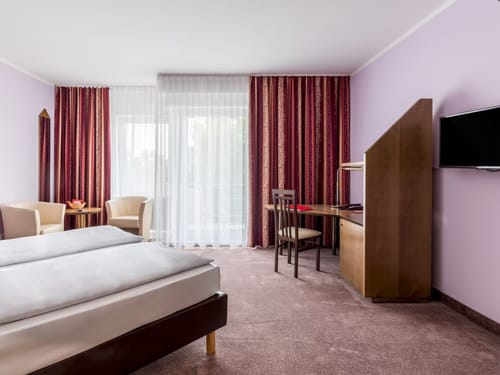 Modernes Hotelzimmer mit Doppelbett, Arbeitsbereich und Sitzgelegenheit.
