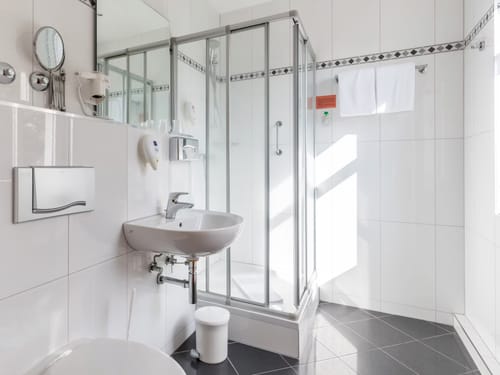 Modernes, helles Badezimmer mit Glasdusche und Wandspiegel.