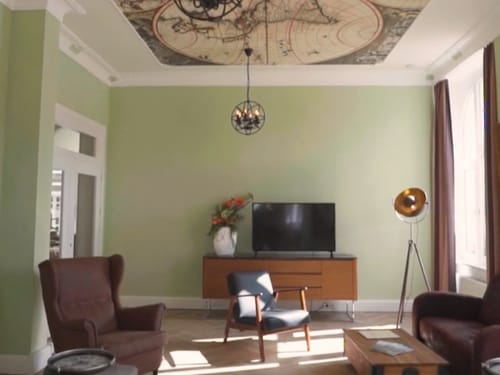 Stilvoll eingerichtetes Wohnzimmer mit vintage Möbeln, einer hängenden Lampe und einer Karte an der Decke.