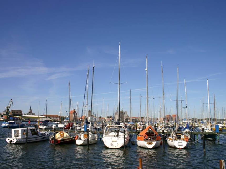 Malerischer Hafen mit Segelbooten am Steg bei sonnigem Wetter.