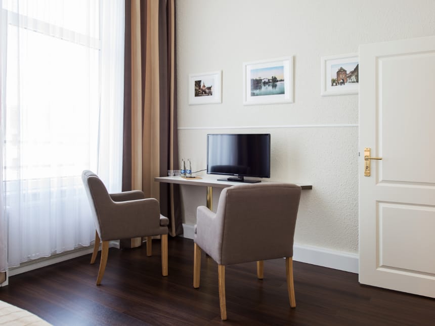 Modernes Hotelzimmer mit gemütlicher Sitzecke und Flachbildfernseher.