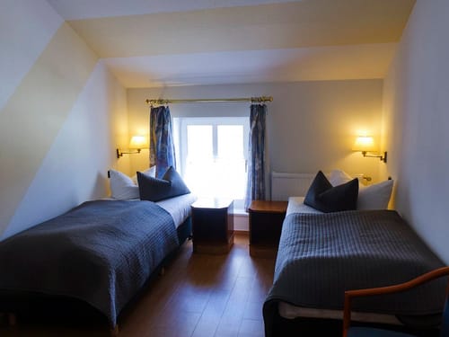 Hotelzimmer mit zwei Einzelbetten – gemütlich eingerichtet mit warmer Beleuchtung
