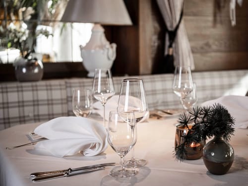 Eleganter gedeckter Tisch in einem stilvollen Restaurant mit Weingläsern und feiner Tischdekoration.