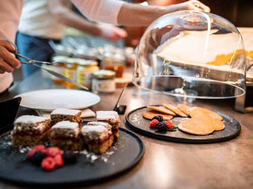 Frischer Kuchen und Pfannkuchen mit Beeren auf einem Buffet.
