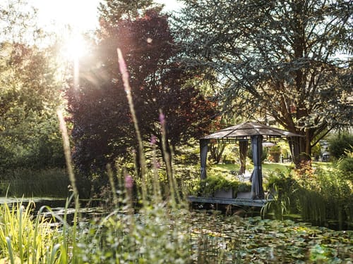 Malerischer Garten mit Pavillon am Teich im Sonnenlicht