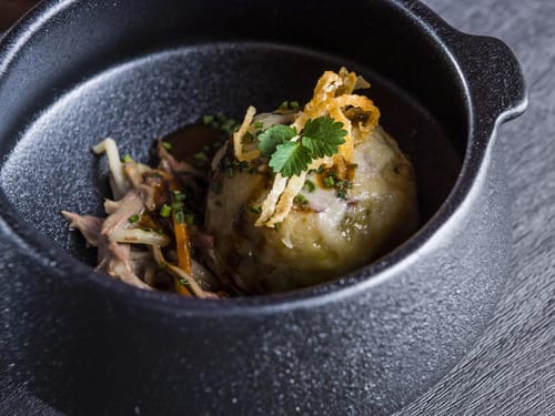Gericht mit Knödel in einem schwarzem Topf serviert
