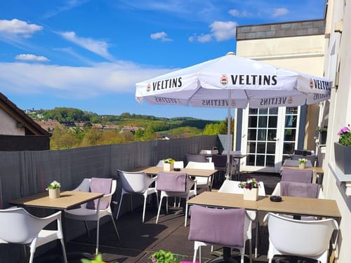 Gemütliche Außenterrasse mit Panoramablick – Restaurant mit Veltins-Schirm