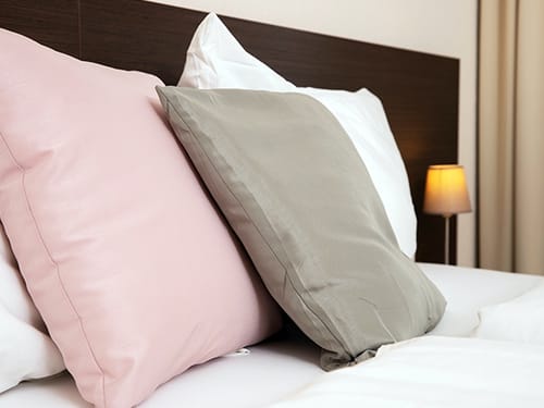 Stilvolles Hotelzimmer mit Kissen in Rosa, Grau und Weiß