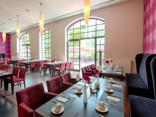 Einladender Frühstücks- und Restaurantbereich mit stilvollem Interieur und natürlichem Licht durch große Bogenfenster