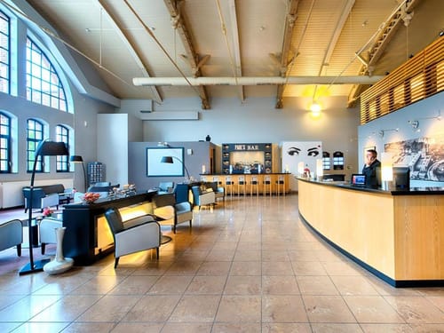 Einladende Hotellobby mit Rezeption, Sitzlounge und Paul's Bar – modernes Design trifft historische Architektur