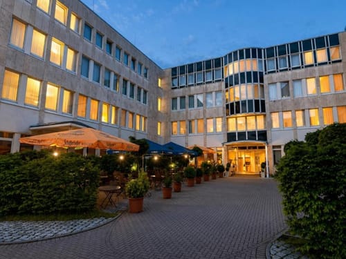 Hotel Außenansicht mit Terrasse und Sonnenschirmen in der Abenddämmerung