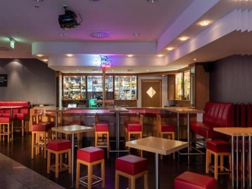 Stilvolle Hotelbar mit rotem Mobiliar und gut sortiertem Spirituosenregal