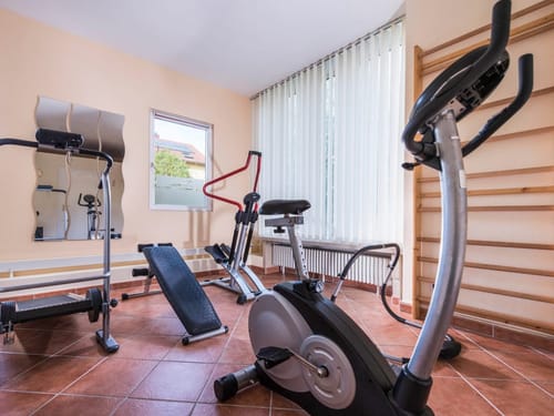 Gut ausgestatteter Fitnessraum mit Heimtrainer, Trainingsbank und Sprossenwand