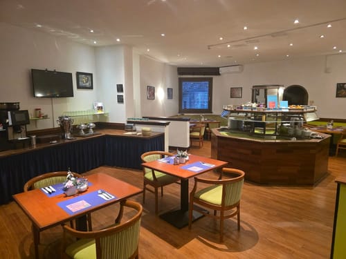 Gemütlicher Restaurantbereich eines Hotels mit rundem Buffet, gedeckten Tischen und warmer Holzoptik für ein entspanntes Frühstück oder Abendessen