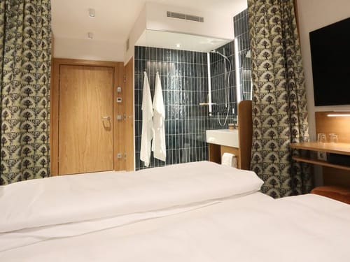 Hotelzimmer mit offenem Badezimmer und Regendusche – modernes Design
