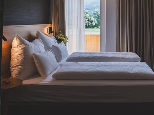 Modernes Hotelzimmer mit Doppelbett und Balkon – Komfort und Natur