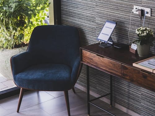 Stilvoller Arbeitsbereich mit blauem Sessel und Holzschreibtisch – Till Naturhotel