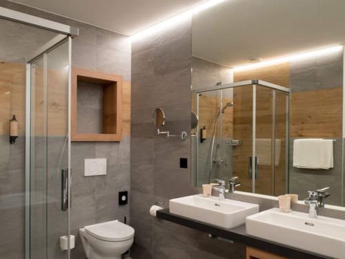 Elegantes Badezimmer mit Doppelwaschbecken und ebenerdiger Dusche im Hotel