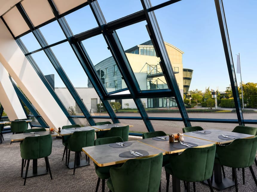 Elegantes Restaurant mit spektakulärer Glasfront und grünen Designerstühlen