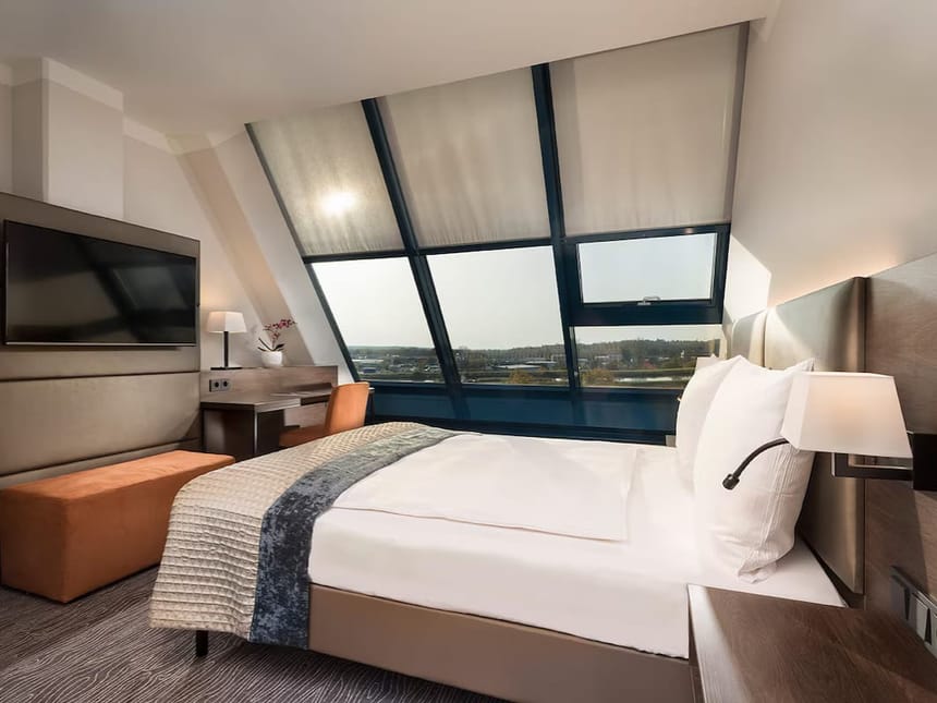 Luxuriöses Hotelzimmer mit Schrägfenster und weißer Bettwäsche
