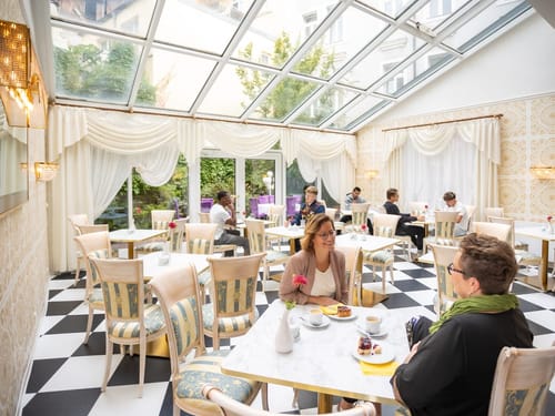 Cafe mit mit Tischen und Stühlen und ein paar Gästen