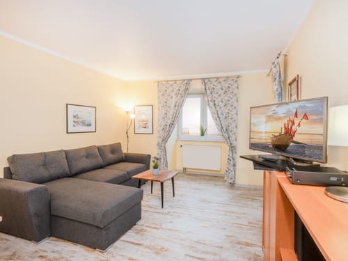 Entdecken Sie ein einladendes Wohnzimmer mit einem komfortablen grauen Sofa, stilvollen Holzmöbeln und dekorativen Elementen. Perfekt zum Entspannen.