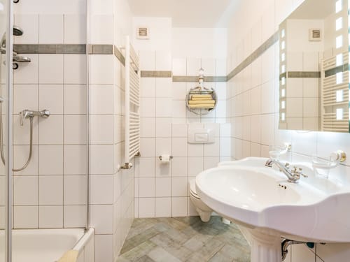 Modernes, helles Badezimmer mit Dusche, Waschbecken und Handtuchhalter