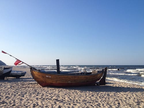Traditionelles Holzboot am Strand mit weitem Meerblick bei klarem Himmel