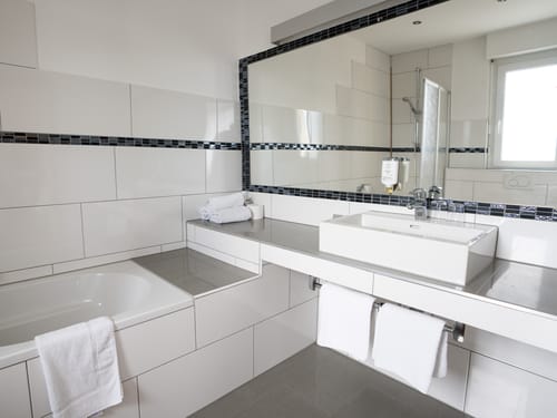 Badezimmer mit großer Badewanne und Waschbecken mit Spiegel.
