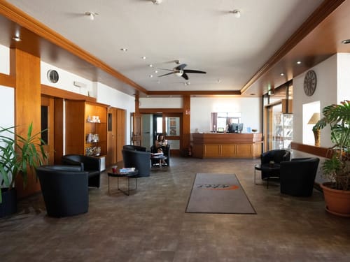 Empfangshalle eines Hotels mit Holzverkleidung, bequemen Sitzgelegenheiten und einer Rezeption.