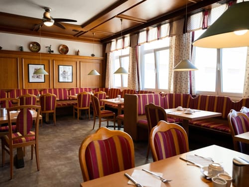 Gemütliches Restaurant mit Holzdekor und gestreiften Sitzpolstern.