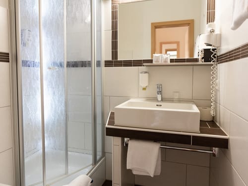 Badezimmer mit Dusche, Waschbecken und Spiegel