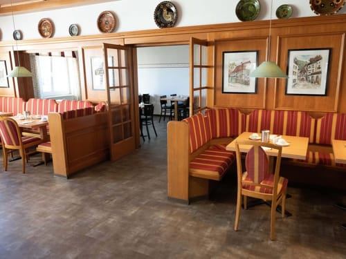 Gemütlicher Frühstücksbereich in einem traditionellen Restaurant mit Holzmöbeln und roten Polsterbänken.