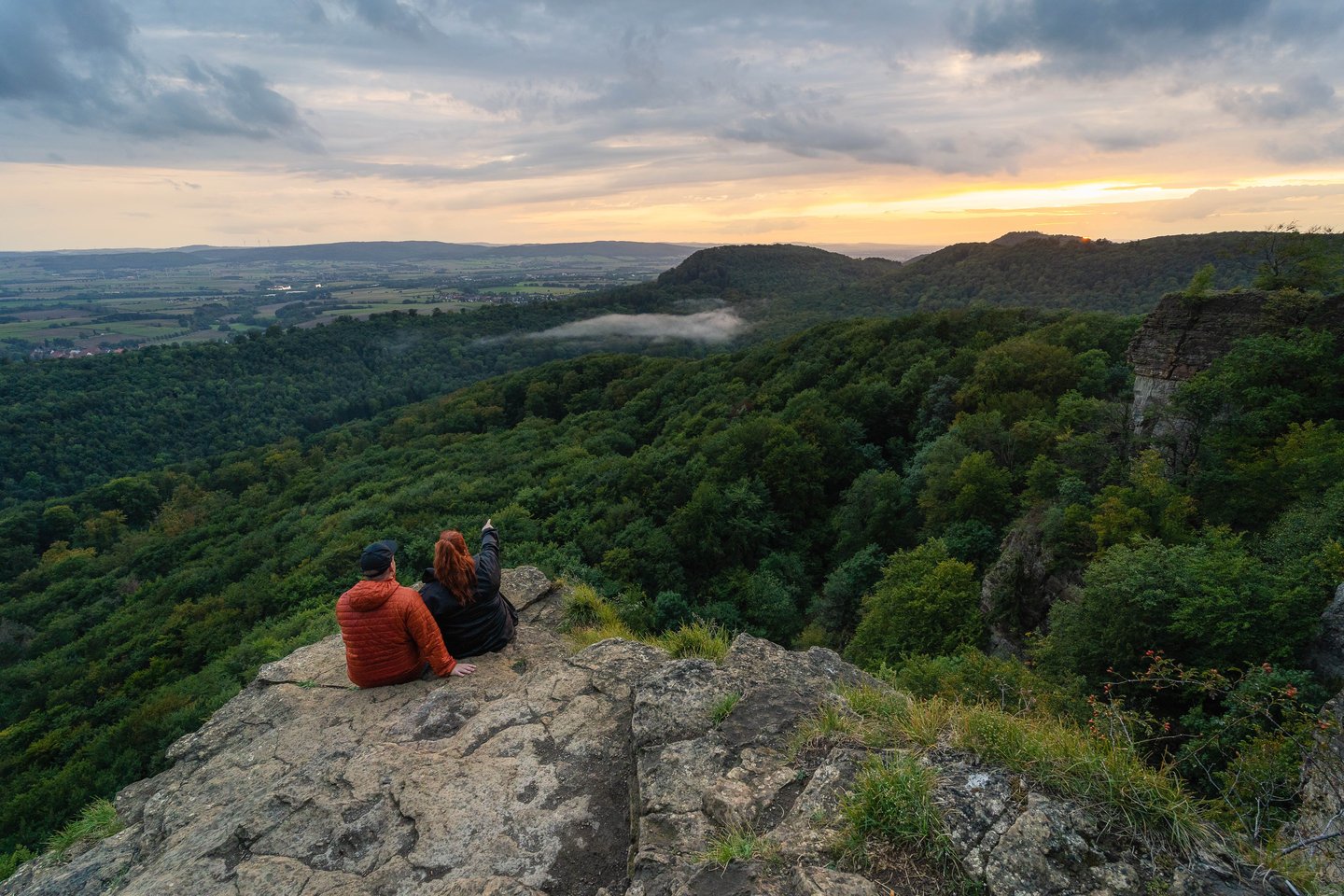 Paar auf den Hohensteinklippen im Weserbergland bei Sonnenuntergang – Rückzugsort für Natur- und Wellnessliebhaber.