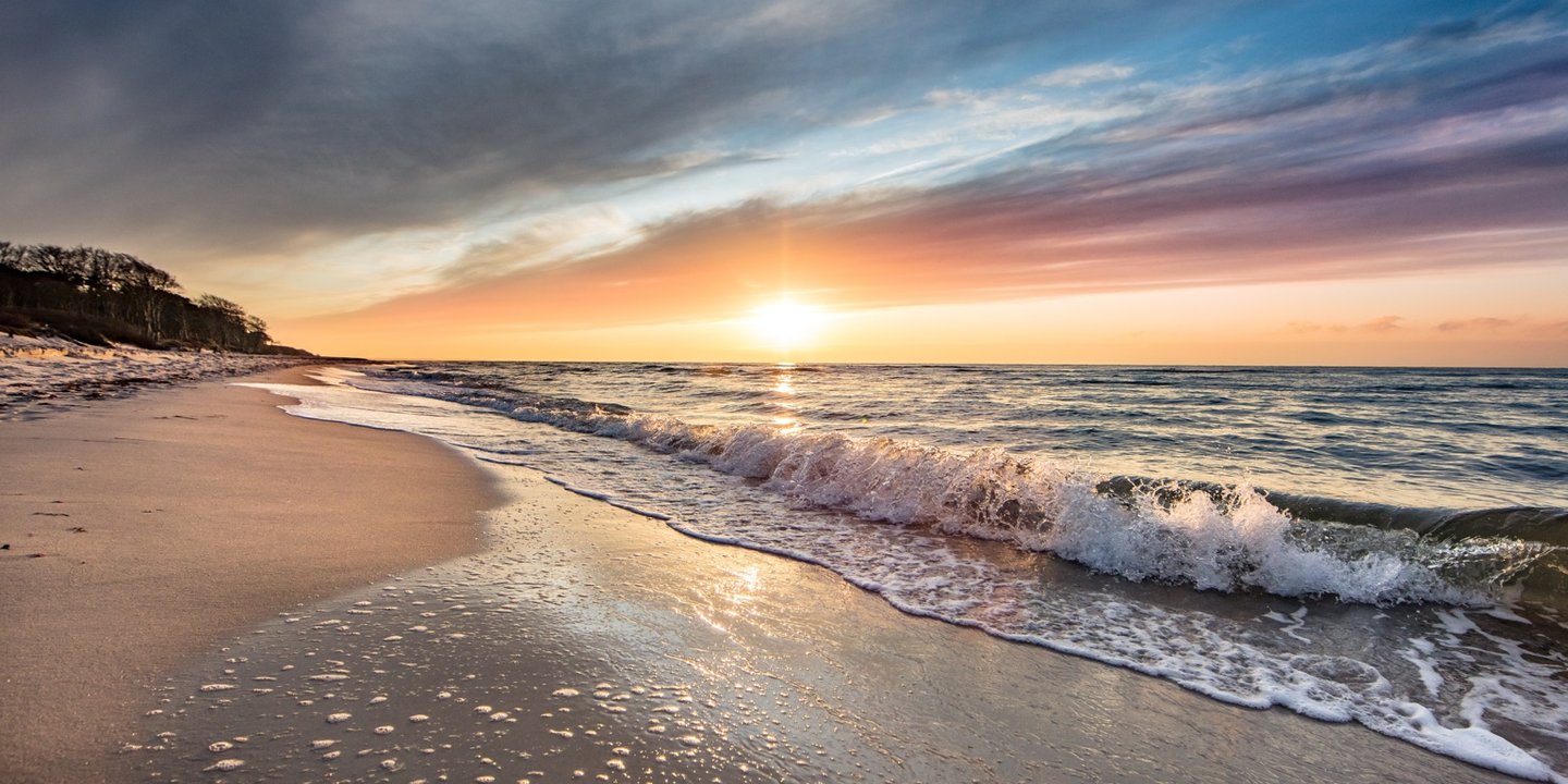 Sanfte Wellen am Ostseestrand bei Sonnenuntergang – stimmungsvolle Kulisse für einen entspannten Urlaub