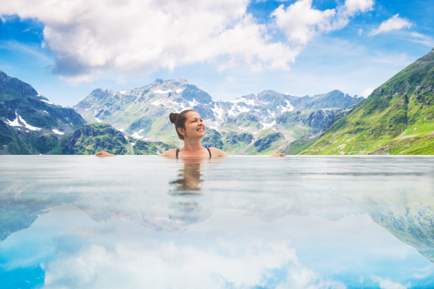 Frau entspannt im Infinity-Pool mit Blick auf das Bergpanorama